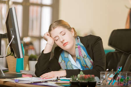 Overworked creative professional woman sleeping at her office deskの写真素材