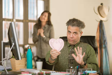 Creative professional man reacting negatively  to Valentine message from coworkerの写真素材