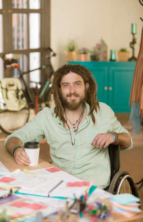 Professional young man in a wheelchair at his office deskの写真素材