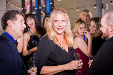 Attractive mature woman with male friends at a partyの写真素材