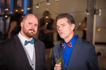 Two skeptical men wearing bow ties at a partyの写真素材