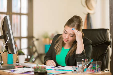 Overworked creative professional woman in her officeの写真素材