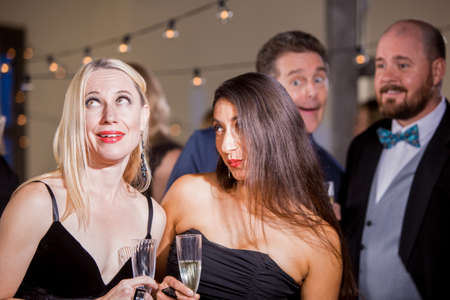 Two pretty women reacting to a couple of men at partyの写真素材