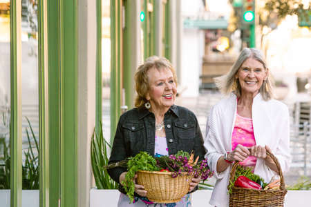 Two senior women returning from farmers market with produceの写真素材