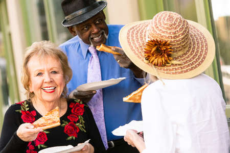 Three seniors downtown eating slices of pizzaの写真素材