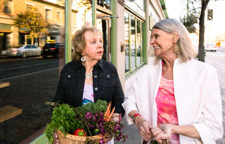 Two women returning with produce from farmers marketの写真素材