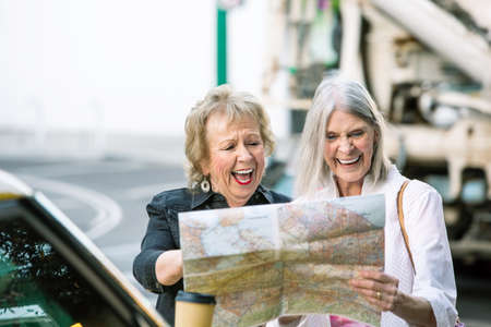 Two laughing women in a city center checking road mapの写真素材