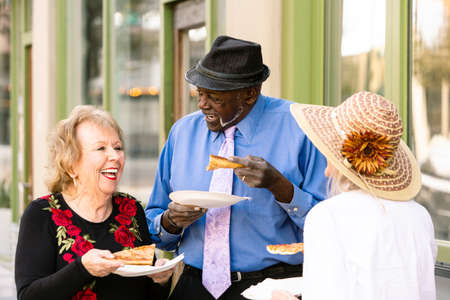 Three seniors downtown with slices of pizzaの写真素材