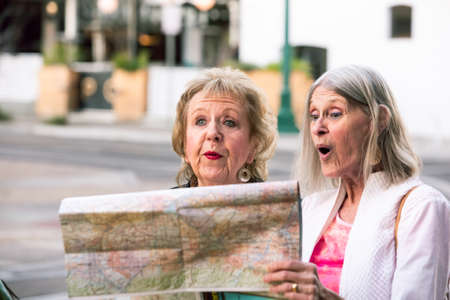 Two senior women in a city center checking road mapの写真素材