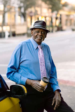 Handsome senior man smiling downtown and leaning against carの写真素材
