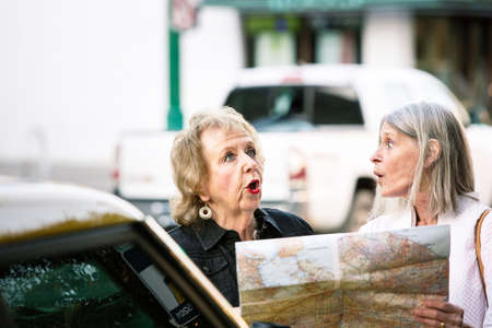 Two women lost in a city center checking road mapの写真素材