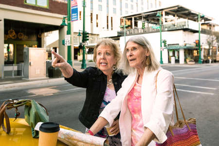 Two women in a city center consulting a road mapの写真素材