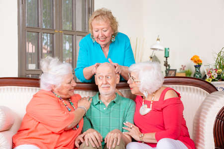 Three senior women giving affection to a nervous manの写真素材
