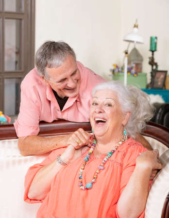 Affectionate senior man and woman at home on couch smilingの写真素材