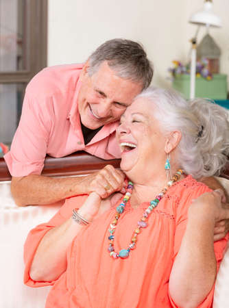 Senior man and woman at home on couch smilingの写真素材