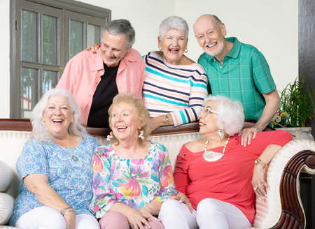 Six laughing senior friends around an antique couchの写真素材