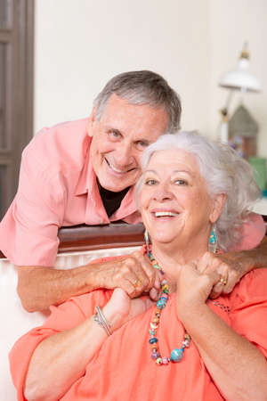 Cheerful senior man and woman at home holding handsの写真素材