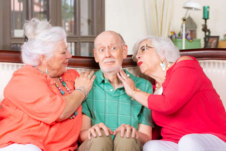 Two senior women giving affection to a nervous manの写真素材