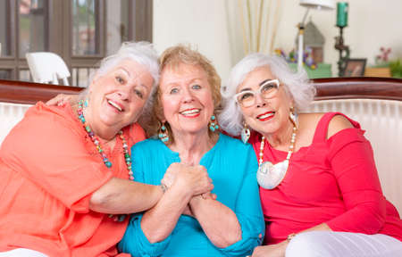 Three senior friends on couch in bright colored clothesの写真素材