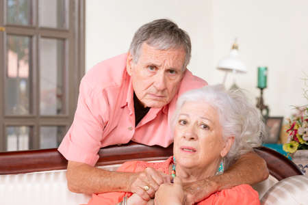 Upset senior man and woman at homeの写真素材