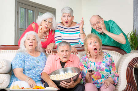 Six upset senior friends reacting to televisionの写真素材