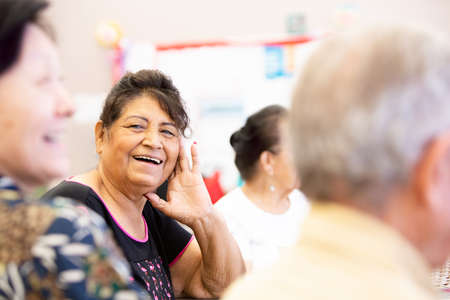 Hispanic woman smiling and talking in a senior centerの写真素材