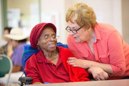 Hispanic and  African American women together in a busy senior centerの写真素材