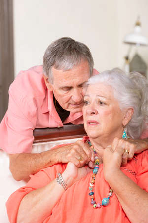 Upset senior man and woman at home embracingの写真素材