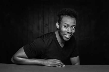 Black and white handsome smiling African American man leaning on a tableの写真素材
