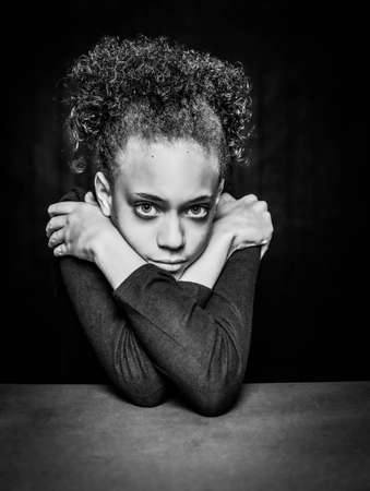 Black and white vertical shot of pretty young girl resting her head on crossed armsの写真素材