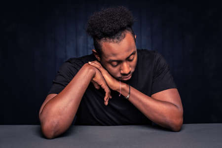 Handsome black man resting his head and looking downの写真素材