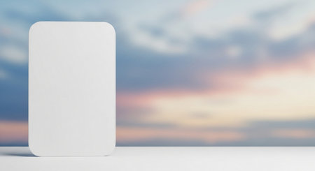 Blank white mobile phone on white table with blurred sky background.の素材