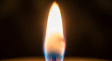 close up of a burning candle on a black background with copy spaceの素材