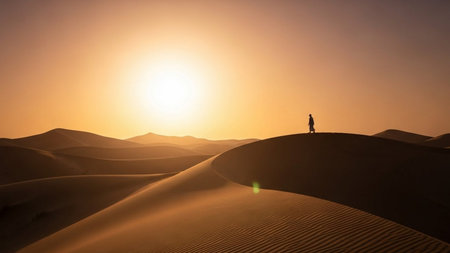 Silhouette of a woman walking in the desert at sunset.の素材
