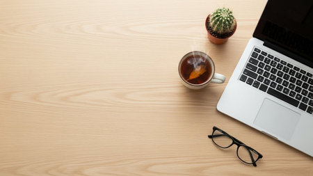 Laptop and cup of tea on wooden table. Top view with copy spaceの素材