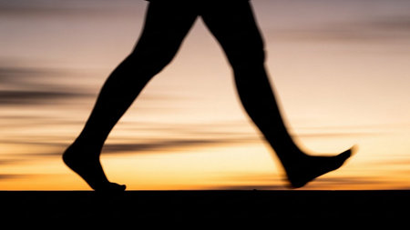 Silhouette of a woman walking on the road at sunset.の素材