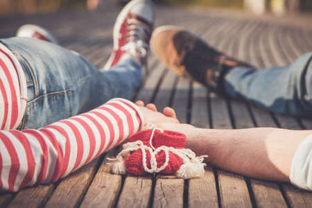 Baby shoes and couple holding hands in anticipation of the babyの写真素材