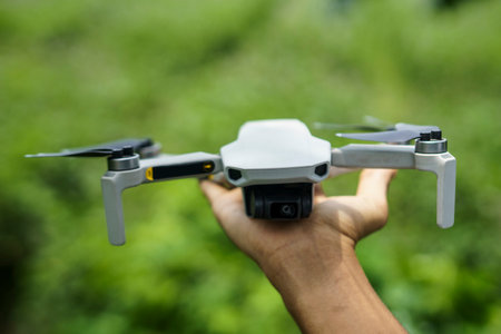 Drone with digital camera in hand on green nature background, technology and agriculture concept
