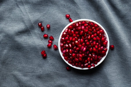 Pomegranate seeds in a bowl on a gray background.の写真素材