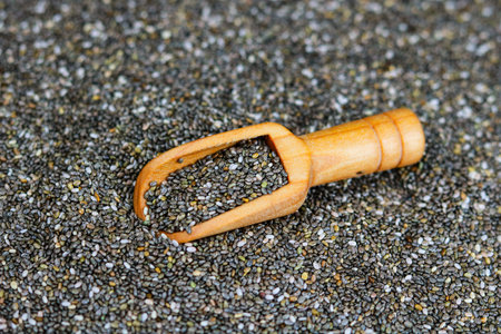 Chia seeds in a wooden scoop on a background of chia seedsの写真素材