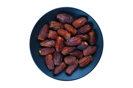 Dried date fruits on a black plate isolated on a white background.