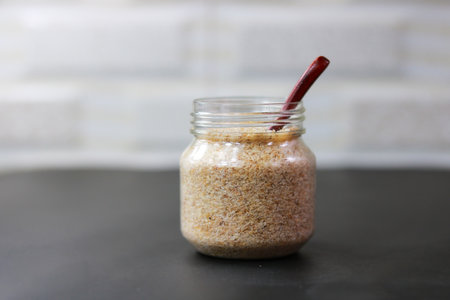 Psyllium Husk (Isabgol) in a glass jar with a wooden spoon on a dark background