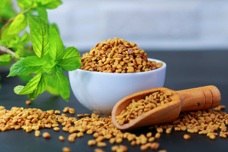 Fenugreek seeds in a bowl with mint leaves on a black backgroundの写真素材