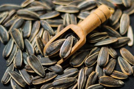 Sunflower seeds in a wooden scoop on a black background. Healthy food.