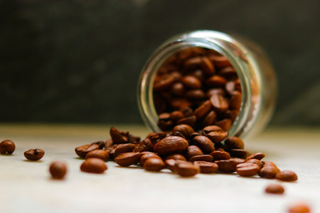 Coffee beans in a glass jar on a wooden table.