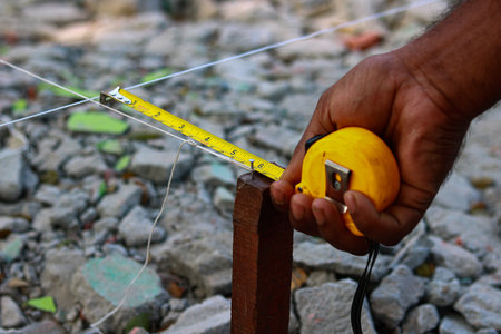 Closeup of a construction worker measuring a wooden beam with a tape measure