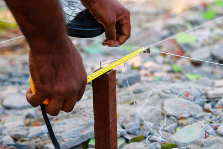 Close up of a construction worker measuring a metal bar with a tape measure