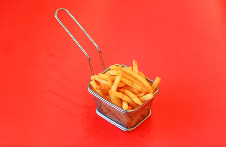 Crispy Golden French Fries in Mini Stainless Steel Serving Basket on Bright Background