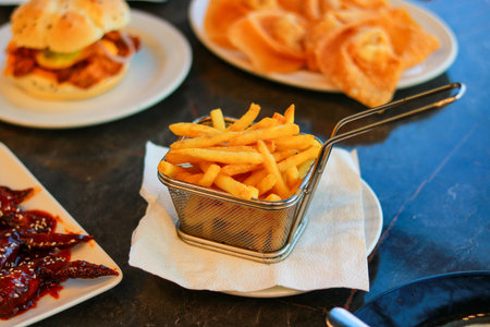 Deep Fried Crispy Potato Fries in Wire Basket Served on a Slate Tableの写真素材