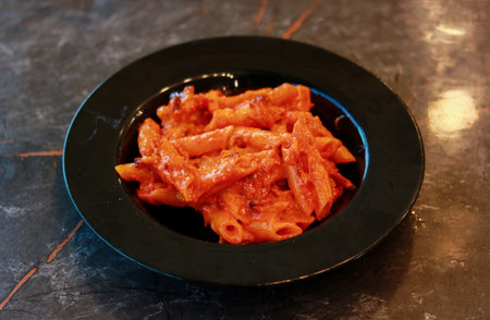 Penne Pasta in Rich Tomato Basil Sauce Served in a Black Bowlの写真素材